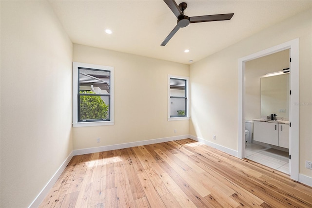 unfurnished bedroom with ceiling fan, ensuite bathroom, sink, and light hardwood / wood-style flooring