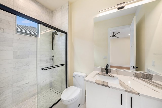 bathroom featuring vanity, a shower with shower door, ceiling fan, and toilet