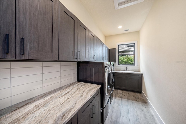 washroom with cabinets, separate washer and dryer, sink, and light wood-type flooring