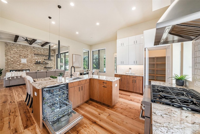 kitchen with sink, white cabinets, island exhaust hood, cooktop, and a large island with sink