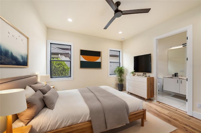 bedroom with ceiling fan, ensuite bathroom, sink, and light hardwood / wood-style flooring