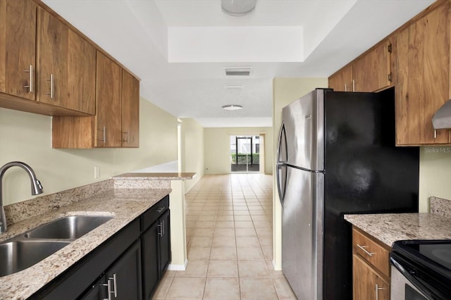 kitchen featuring sink, a raised ceiling, light stone countertops, and light tile patterned floors