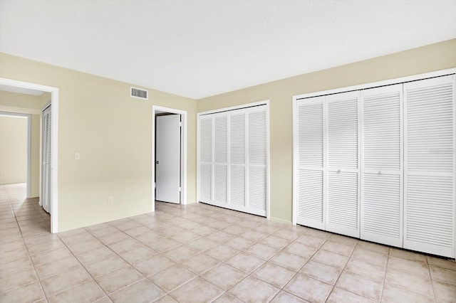 unfurnished bedroom featuring two closets and light tile patterned floors