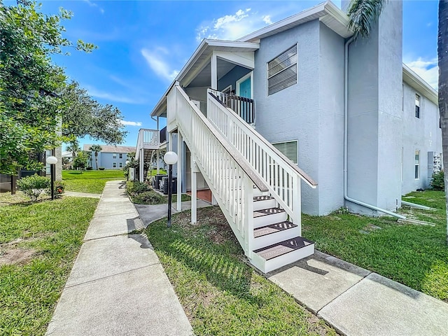 view of side of home featuring stairs, a yard, and stucco siding