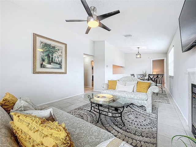 living room with a textured ceiling, ceiling fan, and light tile patterned flooring