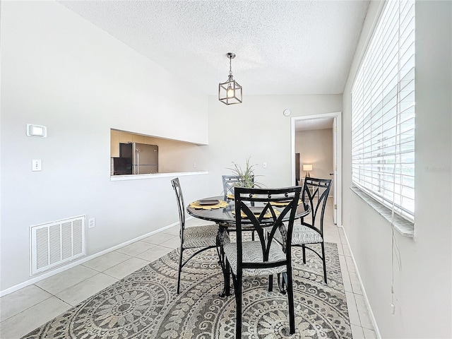 tiled dining room featuring a textured ceiling