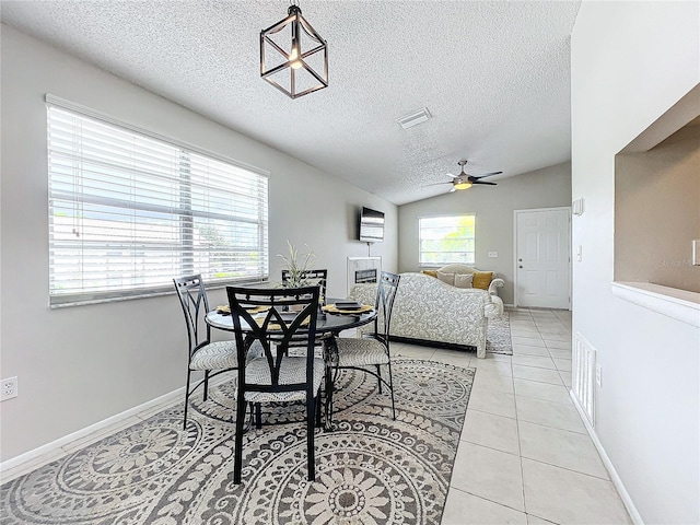 tiled dining area with ceiling fan, vaulted ceiling, and a textured ceiling