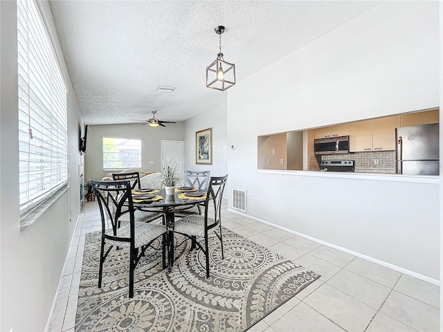 tiled dining area featuring a textured ceiling, ceiling fan, and lofted ceiling