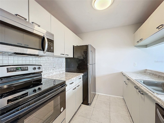 kitchen with decorative backsplash, stainless steel appliances, white cabinetry, a sink, and light tile patterned flooring