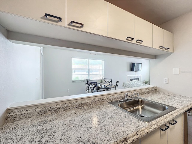 kitchen featuring sink, stainless steel dishwasher, and light stone counters