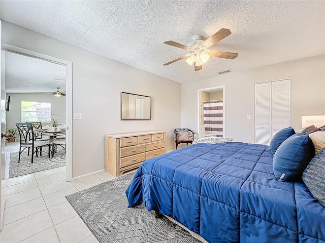 bedroom featuring light tile patterned flooring, a textured ceiling, a closet, and ceiling fan