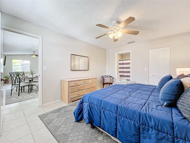 bedroom featuring light tile patterned floors, a textured ceiling, visible vents, and a ceiling fan