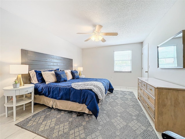 bedroom with a textured ceiling, ceiling fan, and light tile patterned floors