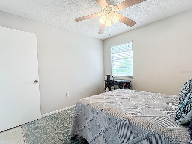 tiled bedroom with ceiling fan and a textured ceiling