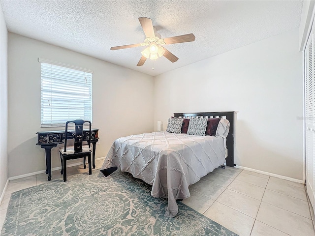 bedroom with a textured ceiling, ceiling fan, and light tile patterned flooring