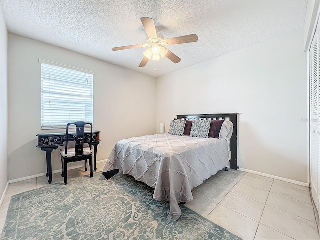 bedroom with a textured ceiling, ceiling fan, baseboards, and tile patterned floors