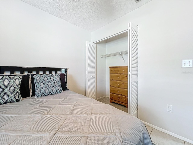 tiled bedroom featuring a closet, a textured ceiling, and baseboards