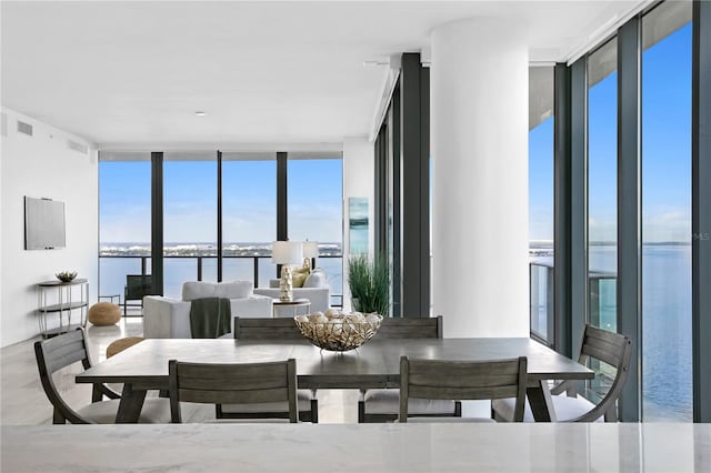 dining space featuring a water view, visible vents, and floor to ceiling windows