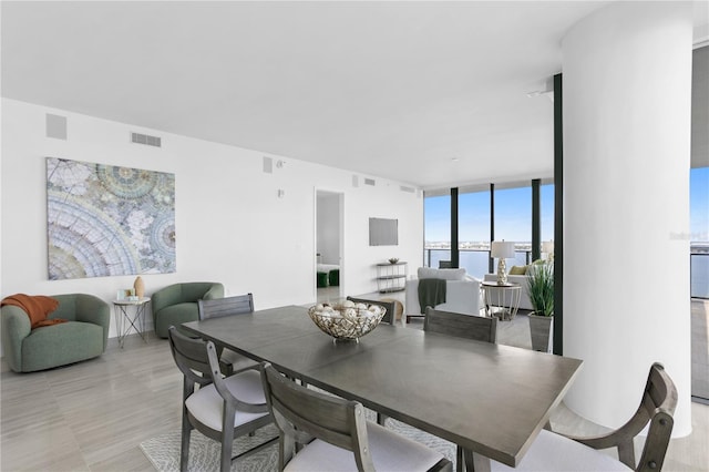 dining room featuring a water view and a wall of windows