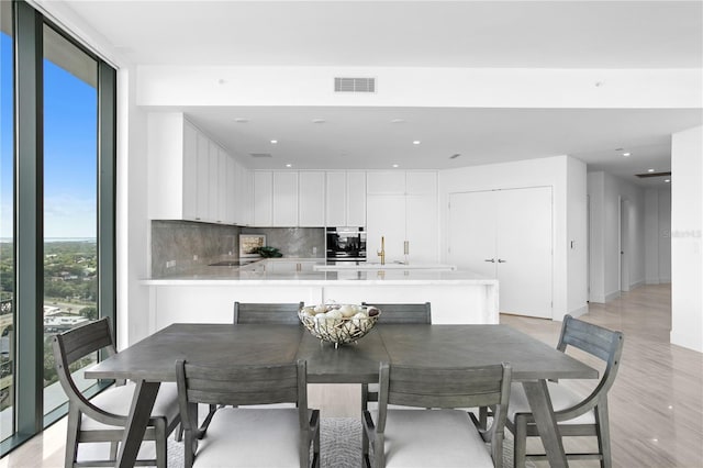 dining area featuring light wood-style floors, visible vents, a wall of windows, and recessed lighting