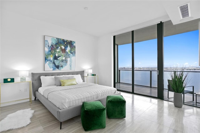 bedroom with access to exterior, expansive windows, visible vents, and a water view