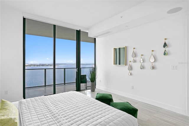 bedroom with multiple windows, a water view, expansive windows, and access to exterior