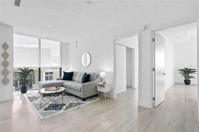 living room with light wood-type flooring and floor to ceiling windows