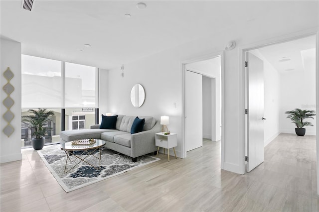 living area with baseboards, expansive windows, and visible vents