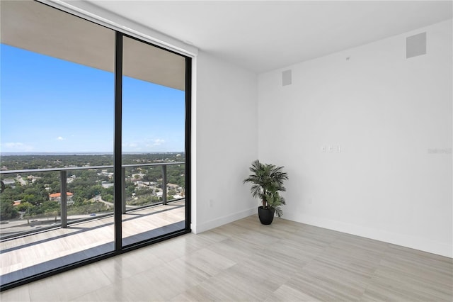 spare room featuring expansive windows, visible vents, and baseboards