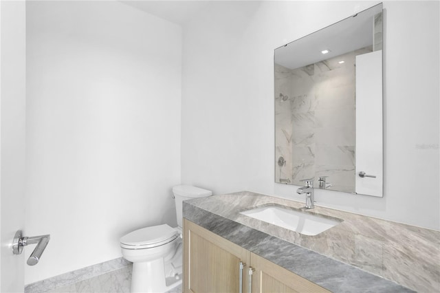 bathroom featuring vanity, toilet, and a tile shower