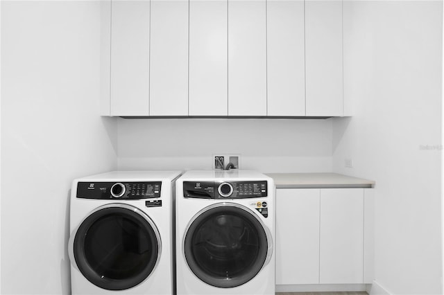 clothes washing area with cabinets and washer and clothes dryer