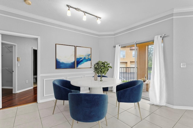 dining space with rail lighting, ornamental molding, and light wood-type flooring