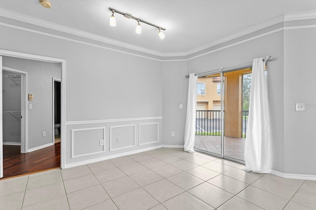 spare room featuring track lighting, tile patterned flooring, and crown molding