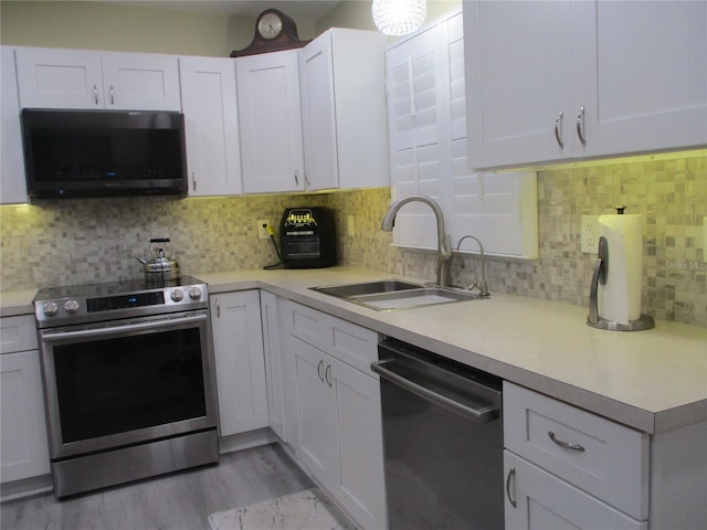 kitchen featuring appliances with stainless steel finishes, sink, light hardwood / wood-style flooring, and decorative backsplash