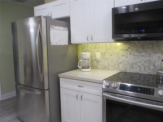 kitchen featuring tasteful backsplash, white cabinetry, appliances with stainless steel finishes, and wood-type flooring