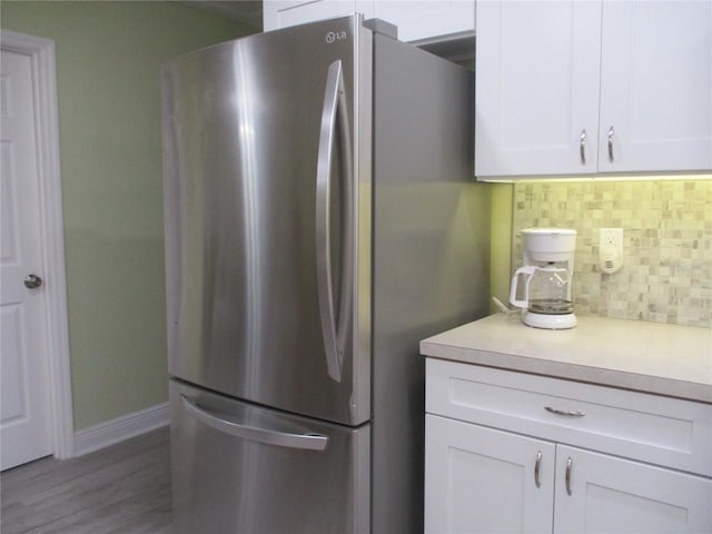 kitchen featuring backsplash, white cabinetry, dark hardwood / wood-style flooring, and stainless steel refrigerator