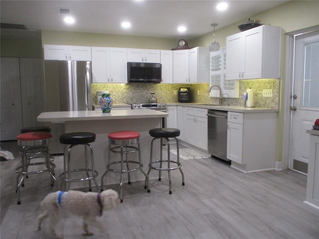 kitchen featuring sink, appliances with stainless steel finishes, light hardwood / wood-style flooring, decorative backsplash, and white cabinetry