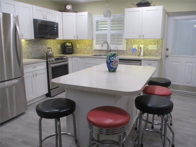 kitchen featuring tasteful backsplash, appliances with stainless steel finishes, light wood-type flooring, and a breakfast bar