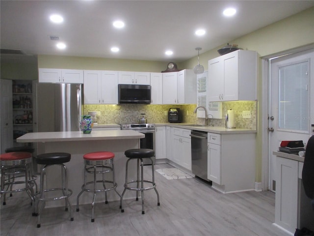 kitchen with stainless steel appliances, decorative backsplash, a kitchen bar, and light hardwood / wood-style flooring