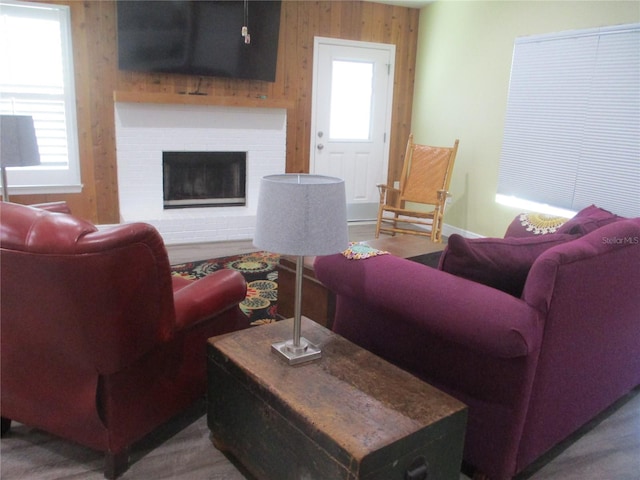 living room with wooden walls, a healthy amount of sunlight, and a brick fireplace