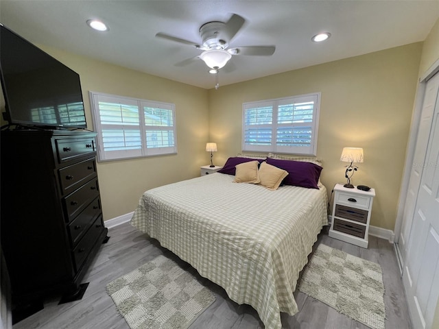 bedroom featuring ceiling fan, a closet, light hardwood / wood-style floors, and multiple windows