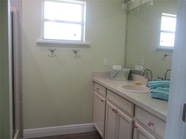 bathroom featuring a shower with shower door and vanity