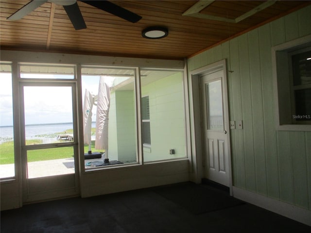 unfurnished sunroom with ceiling fan, wood ceiling, a healthy amount of sunlight, and a water view