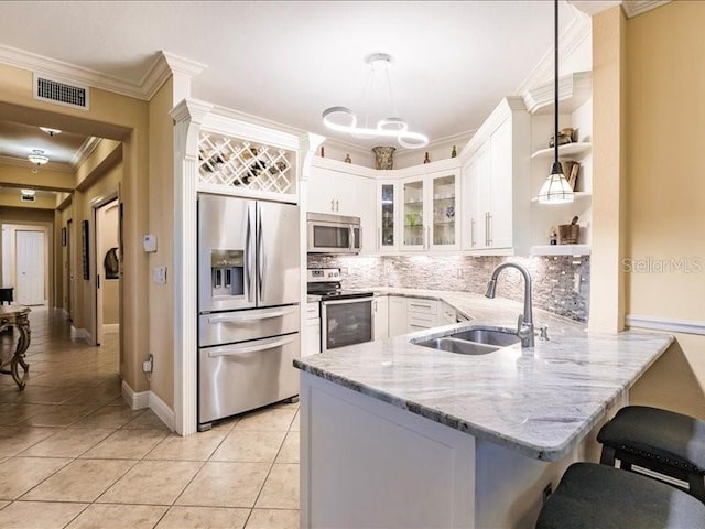 kitchen featuring stainless steel appliances, kitchen peninsula, sink, hanging light fixtures, and white cabinets