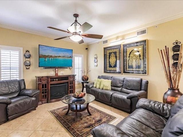 living room with crown molding, plenty of natural light, light tile patterned floors, and ceiling fan