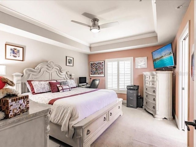 carpeted bedroom with a tray ceiling, ceiling fan, and ornamental molding