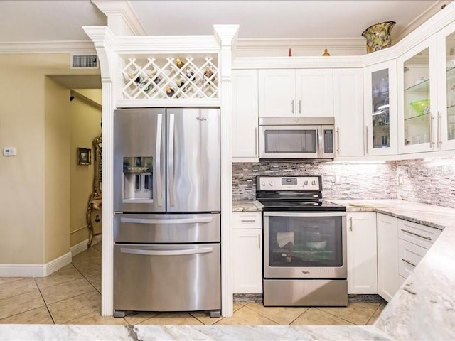 kitchen with crown molding, appliances with stainless steel finishes, light stone counters, white cabinetry, and decorative backsplash