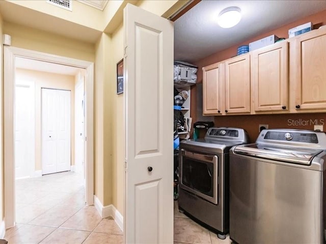 laundry room with light tile patterned floors, cabinets, and washer and dryer