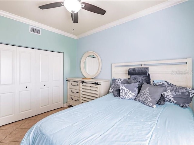 bedroom with light tile patterned floors, ceiling fan, ornamental molding, and a closet