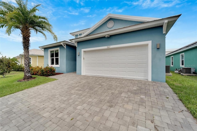 ranch-style house with central AC unit, stucco siding, an attached garage, decorative driveway, and a front yard